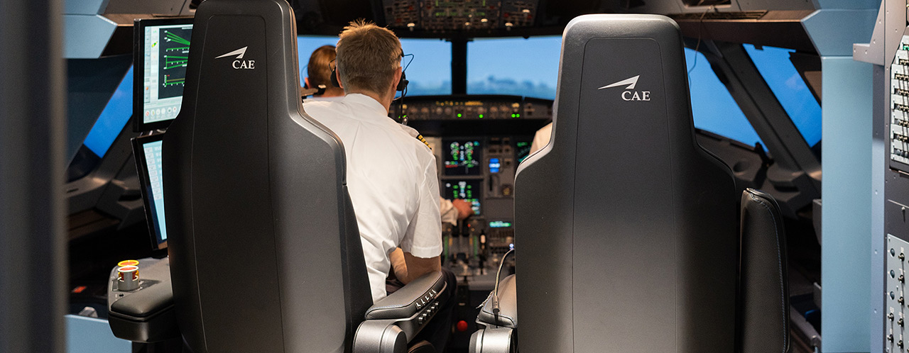 View into a cockpit simulator with 2 persons from behind