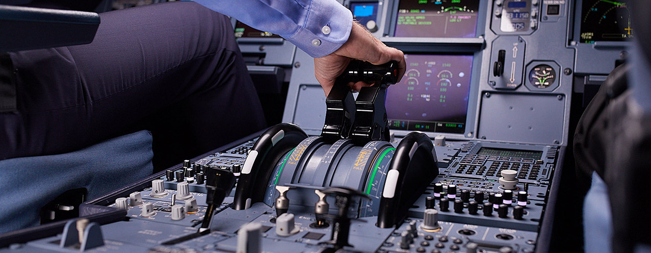 A man operates the thrust control in an aircraft cockpit