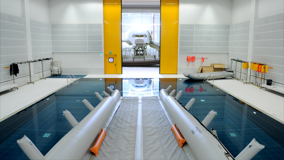 In einer Trainingshalle läuft eine Rettungsrutsche in ein Wasserbassin