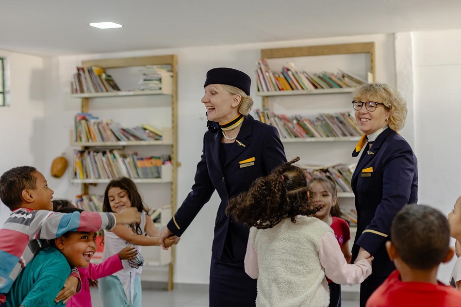 Two Cabincrewmembers wearing their uniform are dancing with children.